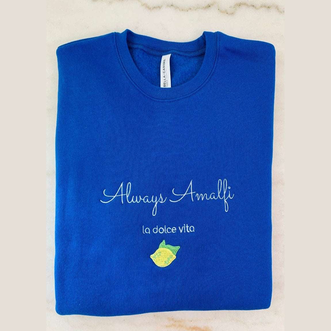 Cream-colored Always Amalfi unisex sweatshirt with classic logo graphic, cozy and stylish Italian-inspired apparel