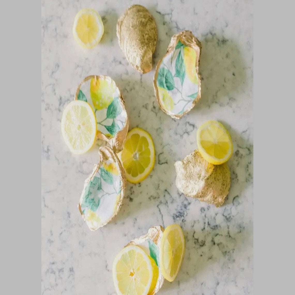 Unique oyster shell jewelry dish with hand-painted lemons and gold trim, offering a touch of coastal elegance to any dresser or vanity