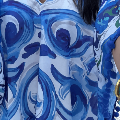 A close-up of a person wearing a blue and white abstract patterned top, styled with a turquoise necklace. The photo appears to be a screenshot from a shopping app, with a 'GET 10% OFF' banner at the bottom.
