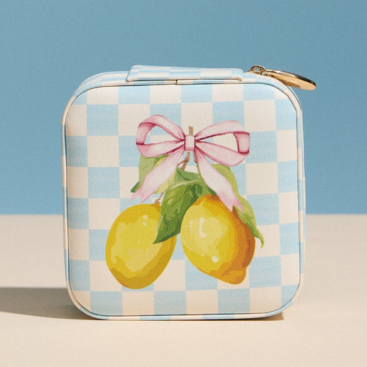 Small rectangular tin with lemon design and pink bow on a checkered pattern against a blue background