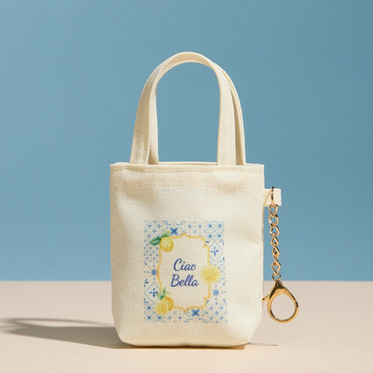 Small beige tote bag with 'Ciao Bella' design and matching keychain on a blue background